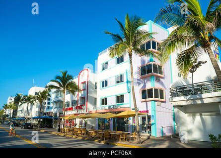 MIAMI - CIRCA Juin 2018 : restaurants sur la bande d'Ocean Drive se tiennent prêts pour les clients du matin en plages du Sud en tant que cycliste rides par. Banque D'Images