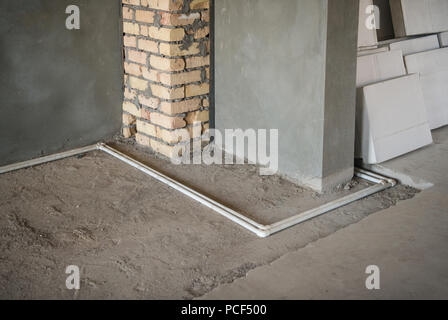 Les tuyaux d'eau en plastique sur le sol et de plâtre des murs dans la nouvelle maison. réparations primaires dans la chambre Banque D'Images