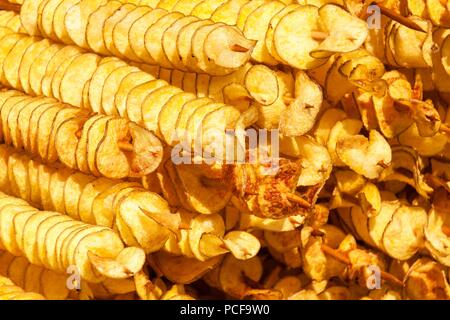 Pommes de terre frites, en spirale sur des bâtonnets de bois, en spirale. Vente de produits alimentaires sur le marché. Les aliments frits. L'alimentation de rue, une spirale sur un bâton de pommes de terre frites Banque D'Images