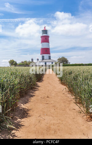 Voir d'happisburgh phare à travers un champ d'orge au début de l'été sur la côte nord du comté de Norfolk uk Banque D'Images