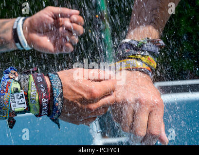 02 août 2018, Wacken, Allemagne : Les Visiteurs du Wacken Open Air Festival se rafraîchir dans la piscine et de garder leurs armes sous l'eau avec le festival bandes. Selon les organisateurs, le plus grand festival de heavy metal commence avec 75 000 visiteurs. Photo : Axel Heimken/dpa Banque D'Images