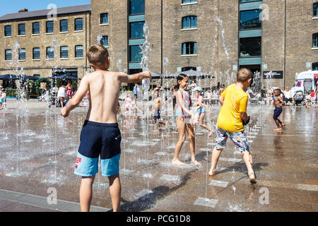 Les familles et les enfants se rafraîchissent dans les fontaines de Granary Square tandis que les températures montent, King's Cross, Londres, Royaume-Uni Banque D'Images