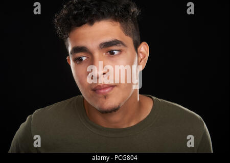 Portrait d'un jeune de 19 ans, dans un t-shirt olive, regardant vers le bas, sur le côté Banque D'Images