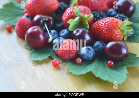 Détail de fruits frais, de baies. Fraises, framboises, cerises, mûres, myrtilles et groseilles rouges sur bamboo board with copy space Banque D'Images