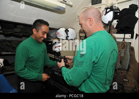 La survie de l'équipage de la Marine américaine Equipmentman aviateur Victor Romero, à gauche, et la survie des équipages de 1ère classe Equipmentman Bruce Pearson, tous deux affectés à l'Escadron d'hélicoptères de combat de la mer (HSC) 9, vérifier des lunettes de vision de nuit avant les opérations de vol à bord du porte-avions USS George H. W. Bush (CVN 77) Juin 27, 2014, dans le golfe Persique. Le navire en charge les opérations de sécurité maritime et les efforts de coopération en matière de sécurité dans le théâtre dans la 5e Flotte des États-Unis zone de responsabilité. Banque D'Images