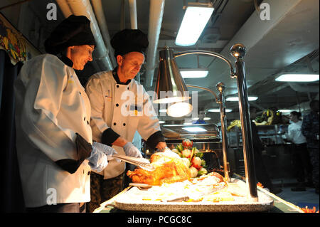 U.S. 5ÈME ZONE DE RESPONSABILITÉ DE LA FLOTTE (nov. 22, 2012) Le chef des opérations navales (CN)) Adm. Jonathan Greenert, droite, sculpte une dinde de Thanksgiving avec son épouse, Darleen, au cours d'une visite à la classe Nimitz porte-avions USS Dwight D. Eisenhower (CVN 69). Dwight D. Eisenhower est déployé sur le 5e Flotte des États-Unis zone de responsabilité des opérations de sécurité maritime, les efforts de coopération en matière de sécurité dans le théâtre et missions d'appui dans le cadre de l'opération Enduring Freedom. Banque D'Images