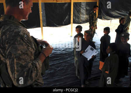 Un garçon Afghan présente ses leçons d'adresses pour un membre de la coalition dans le Tagaw Tagaw, district de la vallée, le 29 août. Banque D'Images