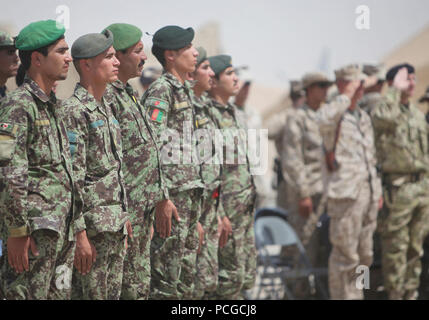 Les diplômés de l'Armée nationale afghane de la lutte contre Cours de médecine au garde à vous aux côtés de leurs mentors de la coalition, des dignitaires et invités pendant leur cérémonie de remise de diplômes à l'Académie de soutien au sud-ouest, Camp Sapadalure, province de Helmand, le 7 juillet. C'était la quatrième édition du cours. Au cours de la formation des soldats de l'ANA ont appris les compétences d'un technicien d'urgence médicale besoins sur le terrain. Banque D'Images