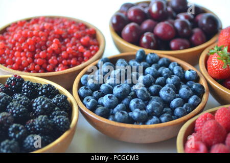 Détail de fruits frais, de baies. Fraises, framboises, cerises, mûres, myrtilles et groseilles rouges dans des bols en bois Banque D'Images