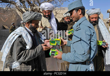 La Police en uniforme afghane distribuer des manuels et des radios pour les anciens du village à Walan Rabat, province de Zabul, Afghanistan, le 31 décembre. Les éléments permettent aux enfants du village de participer à un programme d'alphabétisation radio diffusée localement. Banque D'Images