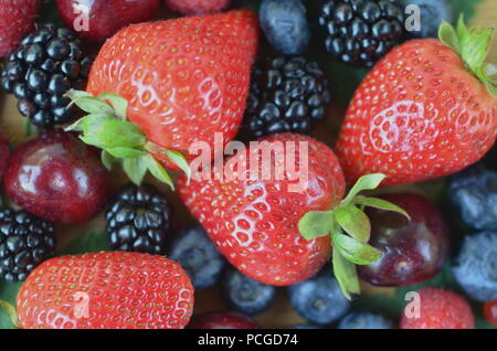 Détail de fruits frais, de baies. Fraises, framboises, cerises, mûres, myrtilles et groseilles rouges sur bamboo board with copy space Banque D'Images