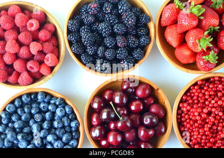 Détail de fruits frais, de baies. Fraises, framboises, cerises, mûres, myrtilles et groseilles rouges dans des bols en bois Banque D'Images