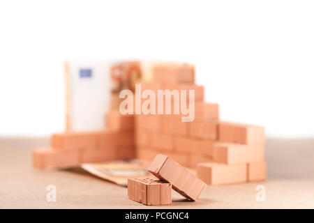 Low angle view sur un coin construit avec de petites briques avec deux 50-billets en euros sur l'angle et de fondation n'est pas mise au point en face de deux pierres. Banque D'Images