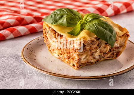 Lasagne traditionnelle faite avec du bœuf haché sauce bolognaise et béchamel garnie de feuilles de basilic. Banque D'Images