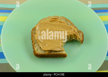 Petit-déjeuner rapide ou une collation de beurre d'arachide sur la tranche de pain avec un morceau pris sur la plaque verte Banque D'Images