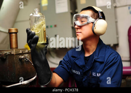 Océan Atlantique (fév. 1, 2013) l'Aviation maître de Manœuvre (fossiles) Airman Allen Mendoza inspecte un échantillon de carburant JP-5 à bord du porte-avions USS George H. W. Bush (CVN 77). George H. W. Bush mène des qualifications de l'opérateur dans l'océan Atlantique. Banque D'Images