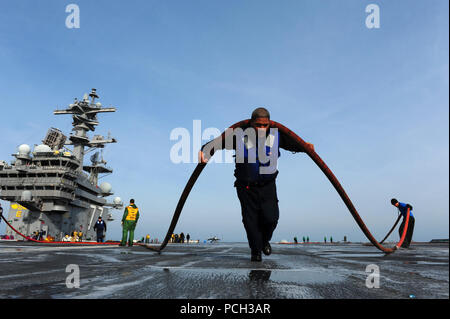 Océan Atlantique (31 déc. 2, 2012) l'Aviation maître de Manœuvre (manutention) Airman David Saili déplace un flexible à travers le pont d'envol du porte-avions USS George H. W. Bush (CVN 77). George H. W. Bush mène des essais en mer en collaboration avec chantier naval de Norfolk à former des marins et d'assurer l'opérabilité de l'équipement et des systèmes à compter de l'expiration d'une période de quatre mois, la période de disponibilité supplémentaires prévues. Banque D'Images