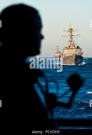 Océan Pacifique (oct. 25, 2012) est un marin montre sur l'arrière du porte-avions USS Nimitz tandis que les destroyers de classe Arleigh Burke USS Stockdale (DDG 106) et l'USS Shoup (DDG 86) suivre derrière détroit pendant une simulation de transport en commun. La Marine américaine est constamment déployés pour préserver la paix, protéger le commerce, et de dissuader l'agression par la présence de l'avant. Inscrivez-vous à la conversation sur les médias sociaux à l'aide de # la guerre. Banque D'Images