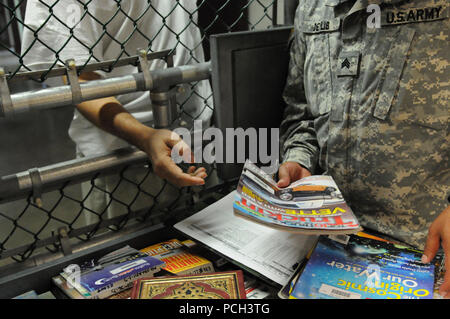 GUANTANAMO BAY, Cuba - Un soldat de la bibliothèque détenu entre les mains un périodique d'un détenu au Camp 5, 16 février. JTF Guantanamo fournit sûr, humain, juridique et transparent le soin et la garde des détenus, y compris ceux qui ont été condamnés par une commission militaire et ceux commandés libéré par un tribunal. La foi mène des activités de collecte, d'analyse et de diffusion pour la protection des détenus et du personnel travaillant dans la foi et à l'appui des installations de Guantanamo de la guerre contre le terrorisme. Guantanamo la foi apporte un soutien à l'Office de Tourisme de Commissions militaires, à la police et aux crimes de guerre investig Banque D'Images