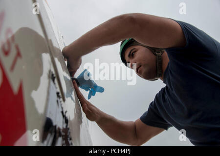 NAVAL AIR FACILITY ATSUGI, au Japon (31 déc. 17, 2015) --électricien Aviation aviateur Joseph Dossing, affecté à l'Escadron d'approvisionnement logistique de la flotte (RVC) Détachement 30 5 Ligne Shack, bandes des gants en latex sur l'électronique sensible de l'eau pendant le lavage d'un aéronef. La ligne Shack est responsable de maintenir les deux de RVC 30 det. 5 avions et s'assurer qu'ils sont propre et prêt pour le vol. Banque D'Images