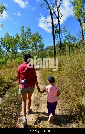 Une mère et des enfants descendre une route poussiéreuse sèche stérile, Townsville, Queensland, Australie Banque D'Images