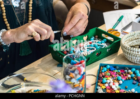 Les mains à l'aide d'une pince pour faire un bracelet en utilisant du métal et du plastique accessoires travaillant à son atelier. Banque D'Images