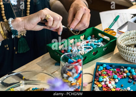Les mains à l'aide d'une pince pour faire un bracelet en utilisant du métal et du plastique accessoires travaillant à son atelier. Banque D'Images