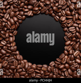 Café en grains formant un cercle sur fond sombre Banque D'Images
