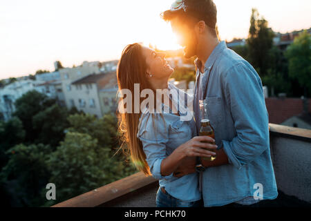 Couple flirting tout en prenant un verre sur la terrasse sur le toit Banque D'Images