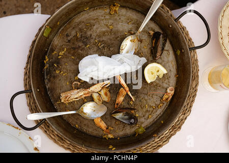 Un déjà mangé la paella poêle avec deux cuillères. Parties de crabes et de palourdes sont autour de la pose dans la vieille casserole. Banque D'Images