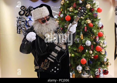 Un acteur habillé en père Noël est titulaire d'une guitare à l'occasion du lancement du Selfridges boutique de Noël au flagship sur Oxford Street, Londres, 145 jours avant Noël. Banque D'Images