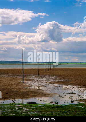 Voir W sur Holy Island Sands, Northumberland, Angleterre, à demi-marée montrant poteaux marquant l'ancienne route de pèlerinage de Chare se termine sur l'Île Sainte à Beal. Banque D'Images