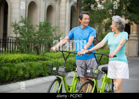 Cheerful senior couple chinois avec le partage de vélos Banque D'Images