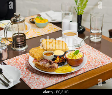 Indian-Nepali traditionnelle assiette petit-déjeuner avec du pain grillé, des œufs brouillés, saucisses, yaourts, fromage, le beurre et le curry. Banque D'Images