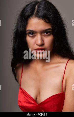 Studio portrait session de 17 ans adolescentes portant une robe rouge sur un fond gris Banque D'Images