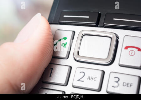 Homme doigt sur le bouton d'appel d'un Telefphone DECT sans fil, prêt à composer ou activer la fonction haut-parleur Banque D'Images