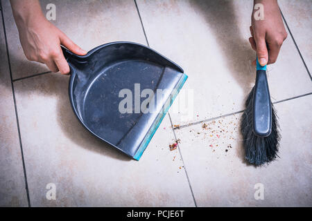 Nettoyer la poussière sur le plancher de tuiles à l'aide d'un pinceau et un porte-poussière retenus par des mains, High Angle View Banque D'Images