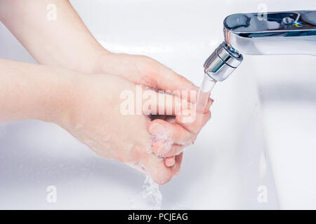 Laver les mains Savonnées sous tourné sur l'eau dans la salle de bains Banque D'Images