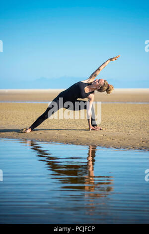 Femme sur la plage de Los Lances faisant un angle de côté yoga pose, Tarifa, Cadix, Andalousie, Espagne Banque D'Images