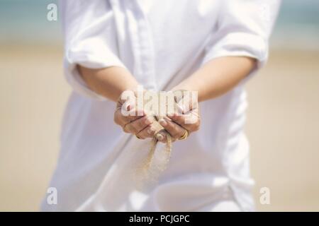 Le sable qui traverse un woman's hands Banque D'Images