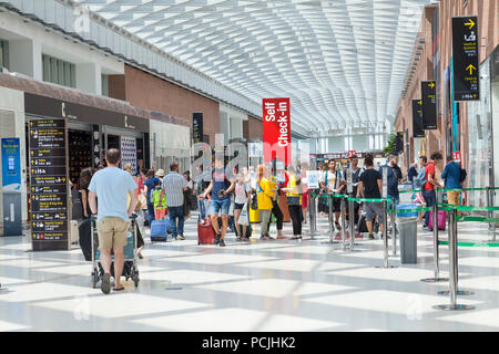 Les passagers à l'aéroport international Marco Polo de Venise, Venise, Vénétie, Italie à l'intérieur du terminal des arrivées avec les familles et les enfants Banque D'Images