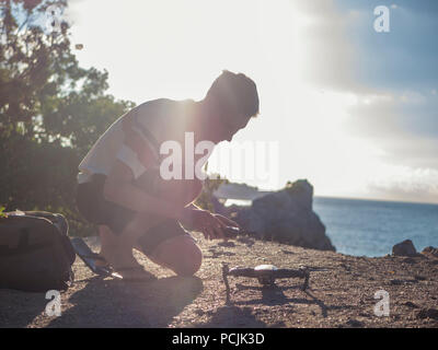 Réglage de l'homme et de contrôle drone avant le décollage sur la montagne paysage près de la mer Banque D'Images