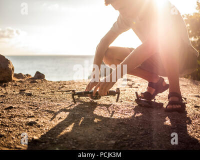 Réglage de l'homme et de contrôle drone avant le décollage sur la montagne paysage près de la mer Banque D'Images