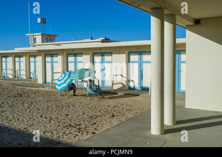 Un couple de chaises longues au soleil par l'emblématique période bleu et blanc des vestiaires par la plage de Trouville-sur-Mer, Normandie, France Banque D'Images