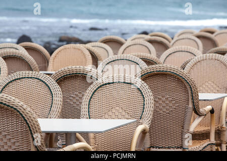 Caleta de Famara/ESPAGNE - Chaises et tables d'un restaurant en plein air avec la mer en arrière-plan, dans la région de Caleta de Famara, Lanzarote, Espagne Banque D'Images