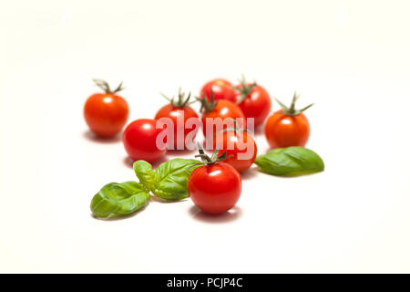 Frais isolé en rouge et orange les tomates cerise avec feuilles vertes de basilic Banque D'Images