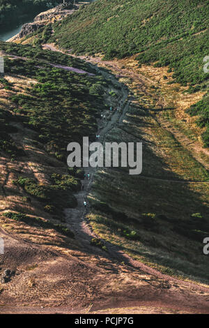 Randonneurs sur le sentier de Holyrood Park, Salisbury Crags et Arthur's Seat au coucher du soleil. Edinburgh, Ecosse, Royaume-Uni. Banque D'Images