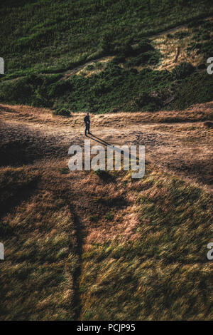 Randonneur sur le sentier de Holyrood Park, Salisbury Crags et Arthur's Seat au coucher du soleil. Edinburgh, Ecosse, Royaume-Uni. Banque D'Images