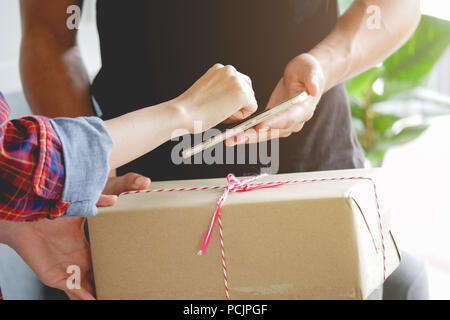 Femme ajoutant signature apposer sur smartphone après recevoir les boîtes du delivery man shopping Banque D'Images