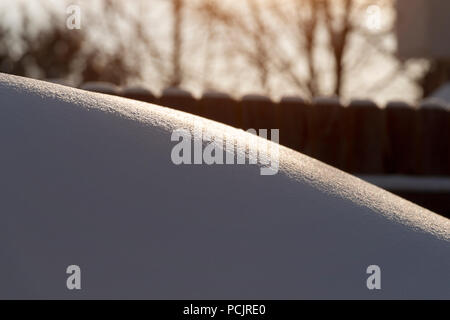 Un grand banc de neige dans l'arrière-cour dans les rayons de l'aube. Banque D'Images